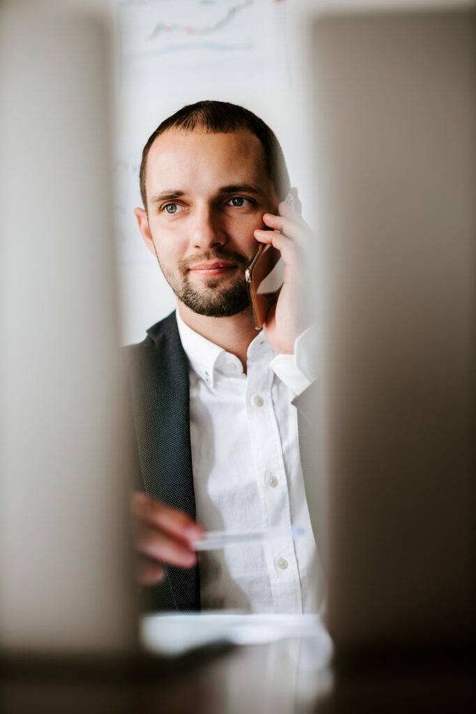 young smiling businessman talking on phone sitting at desk